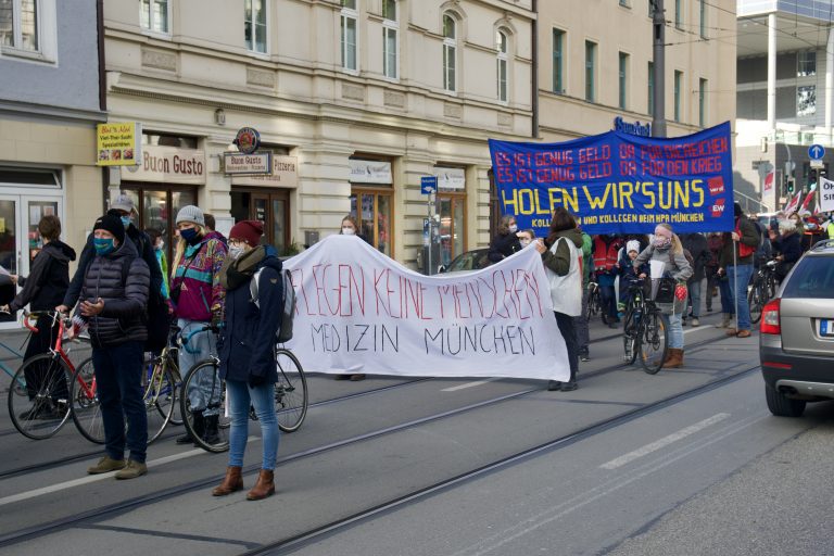 Banner mit Aufschrift "Profite Pflegen keine Menschen" der Kritischen Medizin München und weitere Demonstrantinnen